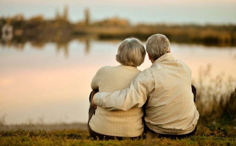Ældre par der holder om hinanden og kigger på en sø